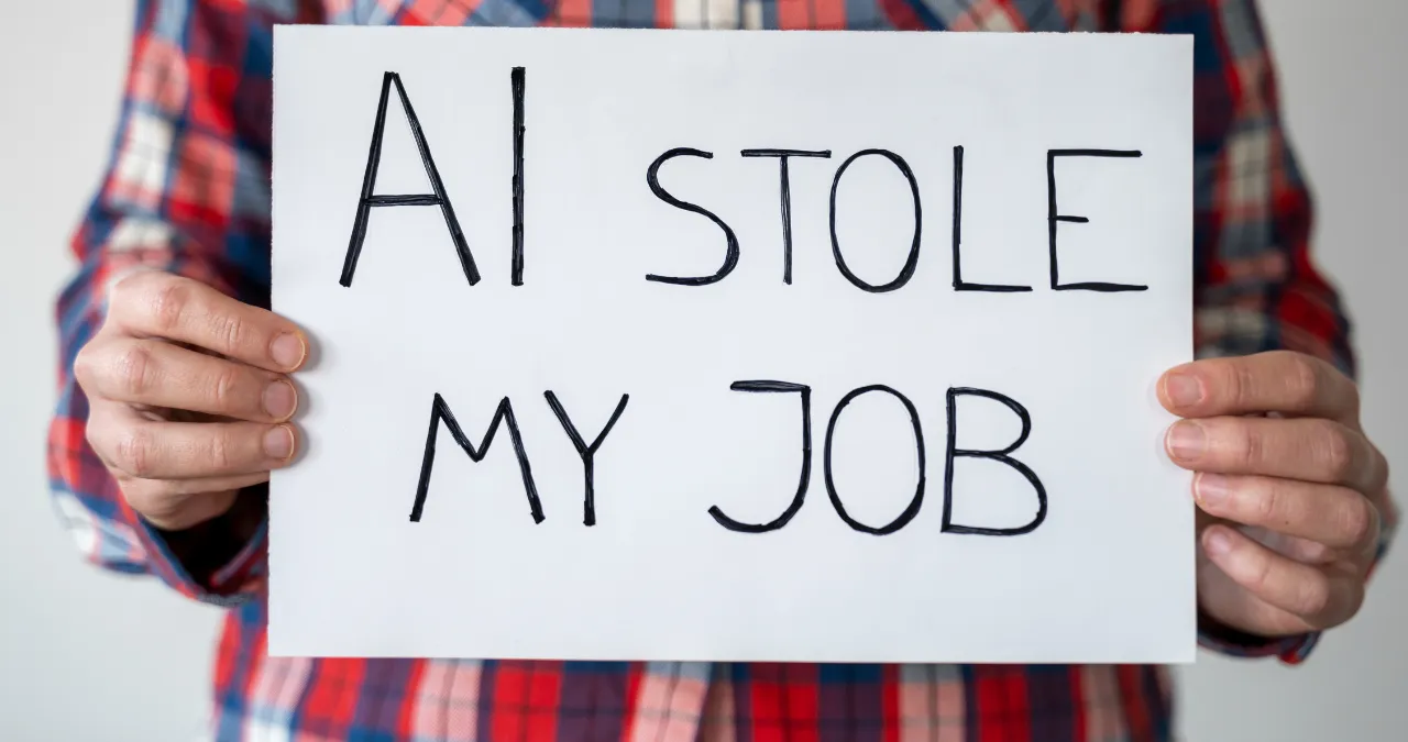 An employee holding white board on his hand and there is written AI stole my job text.